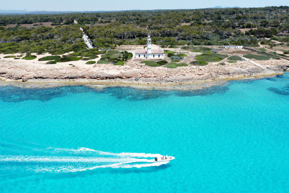 Boat sailing through crystal clear waters in Cala Serena